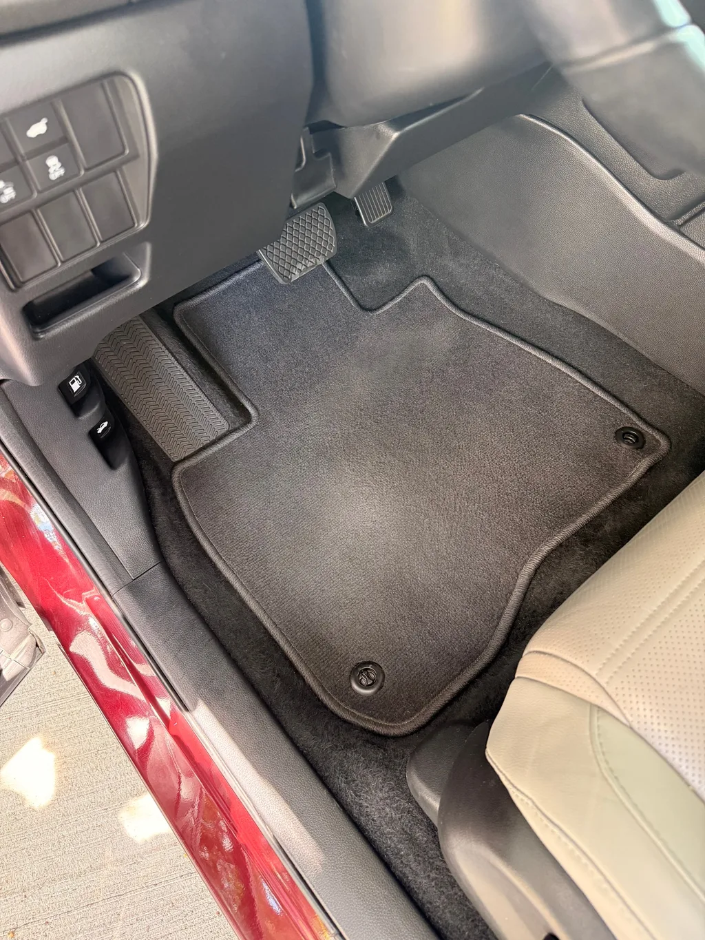 Driver floor mat of the red Honda CR-V after an interior detail, vacuumed clean with no debris left on the carpet