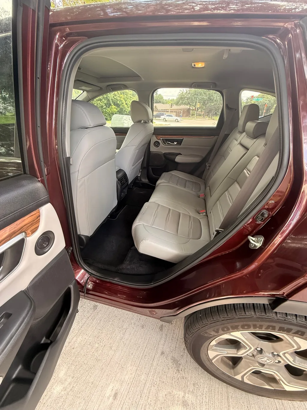 Clean grey leather rear seats of a red Honda CR-V seen through the open rear door after an interior detail, parked on a concrete driveway
